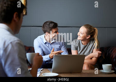 Three Businesspeople Having Meeting In Cafe Stock Photo
