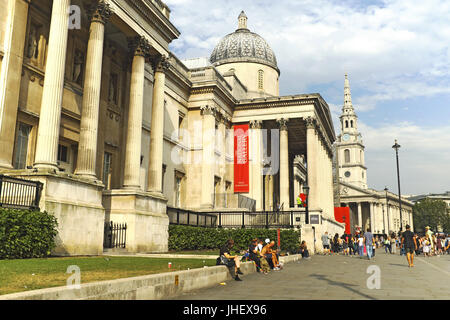 People sit outside the National Gallery on Trafalgar Square in London, England on an August afternoon. Stock Photo