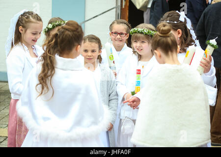 NANDLSTADT, GERMANY - MAY 7, 2017 : A group of young girls holding candles and standing in front of church at their first communion in Nandlstadt, Ger Stock Photo