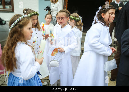 NANDLSTADT, GERMANY - MAY 7, 2017 : A group of young girls holding candles and standing in front of church at their first communion in Nandlstadt, Ger Stock Photo