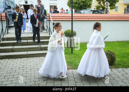 NANDLSTADT, GERMANY - MAY 7, 2017 : Young girls and boys holding candles and heading for the church at their first communion in Nandlstadt, Germany. Stock Photo