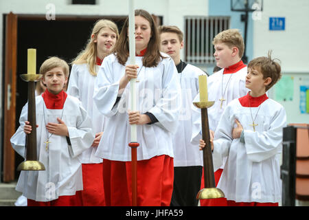 NANDLSTADT, GERMANY - MAY 7, 2017 : A group of altar servers holding candles on stands and leading the communicants at the first communion in Nandlsta Stock Photo