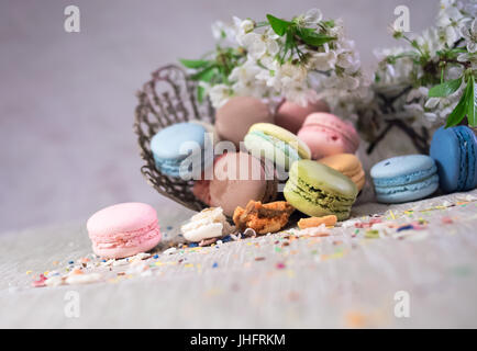 Multicolor macaroons on a table with eastern vase and cherry branch in blossom Stock Photo