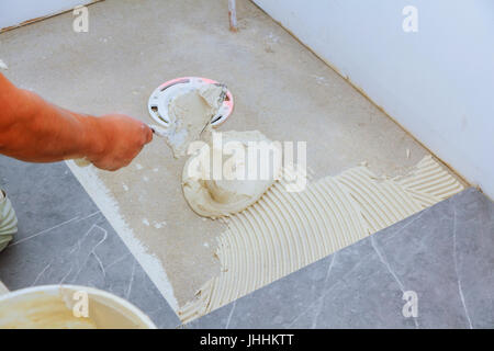 Stylish trendy white ceramic tile with a chamfer on the Tiler hands in the process of laying white rectangular tiles on bathroom wall. Repair of apart Stock Photo