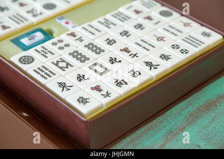 Mahjong '麻將' tiles set and box on green wooden background Stock Photo