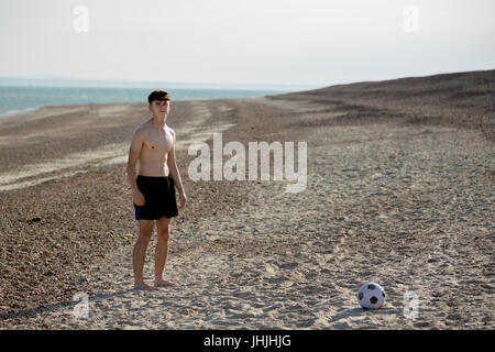 Teenage boy playing with a football on a beach Stock Photo