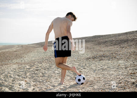 Teenage boy playing with a football on a beach Stock Photo