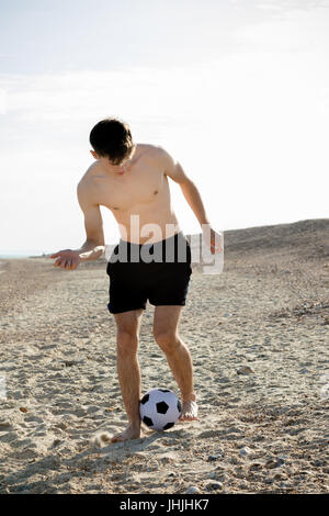 Teenage boy playing with a football on a beach Stock Photo