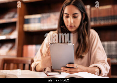 University female student using digital tablet in library. Young female searching information on tablet pc. With focus on digital tablet n female's ha Stock Photo