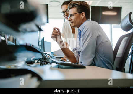 Side view of a mature businessman and businesswoman working together on desktop computer. Two business professionals looking at computer monitor. Stock Photo