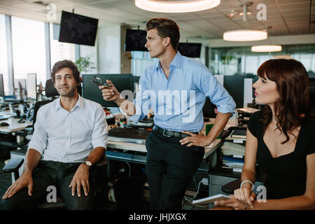 Mature businessman discussing new plans with colleagues during a meeting in modern office. Business people having a meeting in modern office. Stock Photo