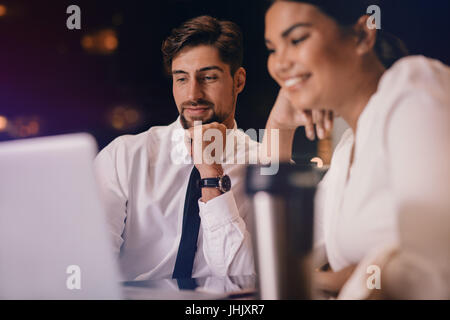 Business man and woman sitting at table and looking at laptop. Business people waiting at airport lounge using laptop computer. Stock Photo