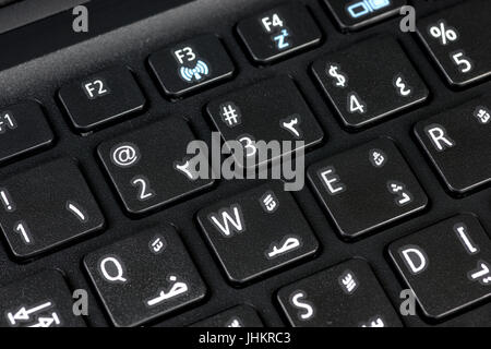 Close-up of a QWERTY keyboard featuring both English and Arabic letters, with visible figures, illustrating bilingual and multicultural communication Stock Photo