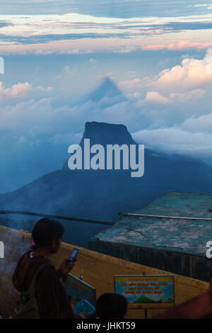 ADAM'S PEAK, SRI LANKA, MARCH 11, 2016 Sunset on the top of Adam's Peak, sacred mountain of Sri Lanka. Pilgrims prays. Stock Photo