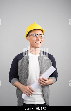 Handsome civil engineer working with documents looking to the side on gray background Stock Photo