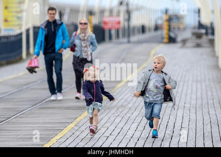 Southport, Merseyside, 14th July 2017. UK Weather.   A much cooler grey evening doesn't stop tourists heading to the pier and seafront at Southport in Merseyside.  With heavy rain downpours expected people were eager to make the most of the dry weather before the rain arrives.   Credit: Cernan Elias/Alamy Live News Stock Photo