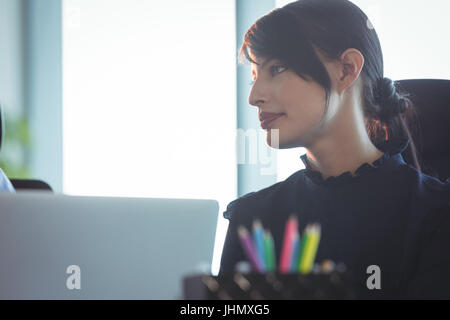 Young thoughtful woman looking away at office Stock Photo