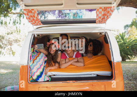 Happy friends taking selfie while lying in camper van at campsite Stock Photo