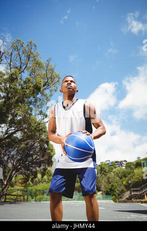 Low angle view of teenage boy practicing basketball i court on sunny day Stock Photo