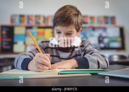 Concentrated schoolboy studying while sitting at desk in classroom Stock Photo