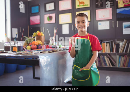 Portrait of smiling boy standing by desk in class at art studio Stock Photo