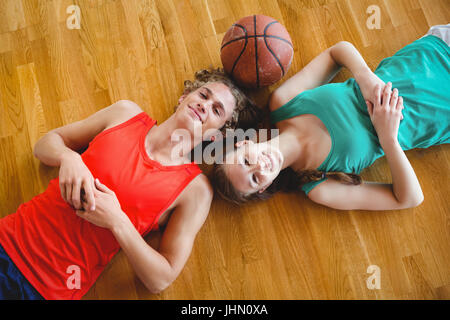 Overhead portrait of friends lying on floor in basketball court Stock Photo