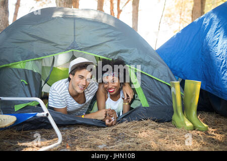 Portrait of couple with arm around relaxing in tent at campsite Stock Photo