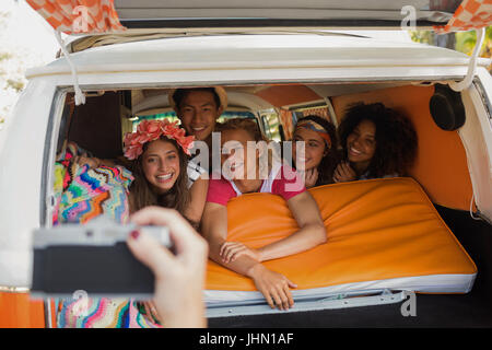 Cropped hand photographing smiling friends lying together in camper van Stock Photo