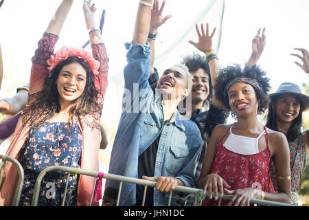 Low angle view of happy friends with arms raised enjoying during music festival Stock Photo