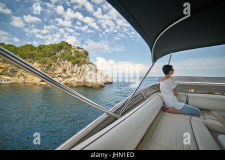 Beautiful slim woman looking out over seascape onboard a luxury yacht Stock Photo
