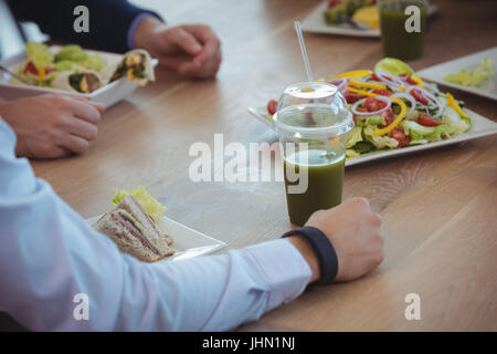 Cropped image of business colleagues having breakfast on table at office cafeteria Stock Photo