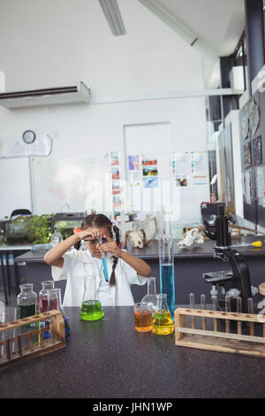 Elementary student doing scientific experiment with blue chemical at science laboratory Stock Photo