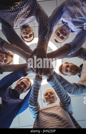 Directly below portrait of business colleagues stacking hands against ceiling at office Stock Photo