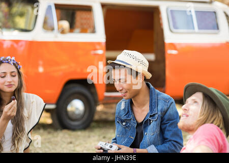 Friends enjoying picnic while relaxing on field Stock Photo