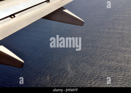Part of an airplane wing with the ocean below. Stock Photo