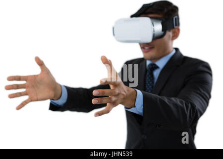 Smiling businessman gesturing while using vr glasses against white background Stock Photo