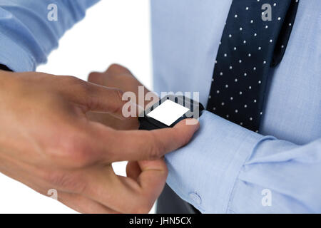 Mid section of businessman using smartwatch against white background Stock Photo