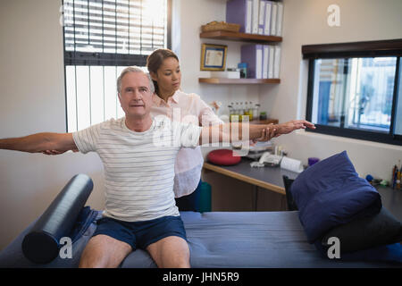 Female doctor examining male patient with arms outstretched at hospital ward Stock Photo