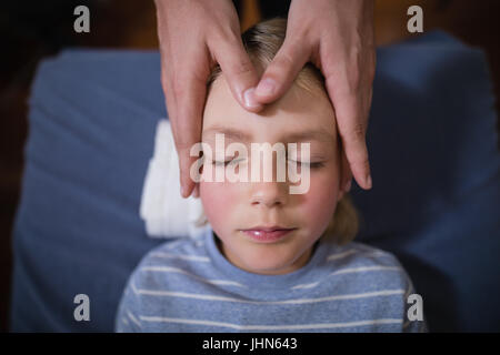 Overhead view of boy receiving head massage from female therapist at hospital ward Stock Photo