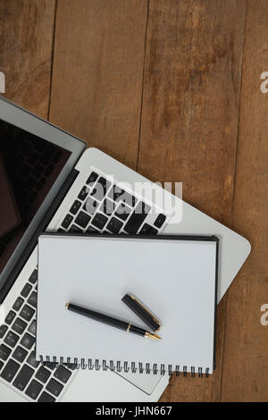 Top view of laptop, pen, and diary on wooden background Stock Photo