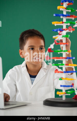 Smiling schoolboy experimenting molecule model in laboratory at school Stock Photo