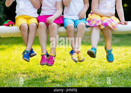 Footwear for children. Group of preschool kids wearing colorful leather shoes. Sandal summer shoe for young child and baby. Preschooler playing outdoo Stock Photo