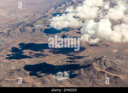 A view from plane on the mountainious countrysite and clouds. Stock Photo