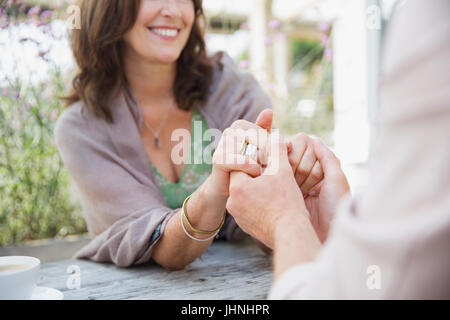 Close up affectionate mature couple holding hands at patio table Stock Photo