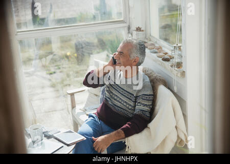 Senior man talking on cell phone on sun porch Stock Photo