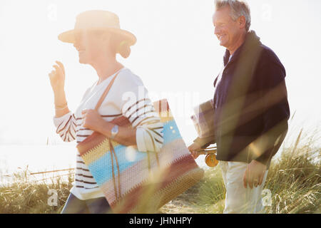 Mature couple walking in sunny beach grass Stock Photo