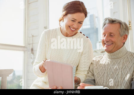 Smiling mature couple using digital tablet on sunny porch Stock Photo