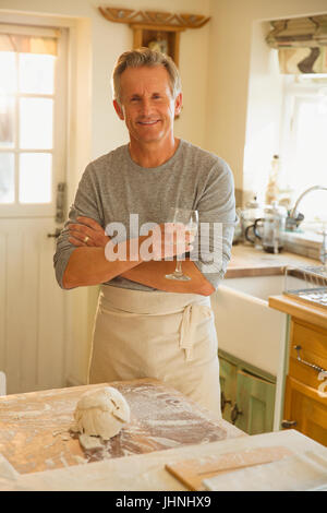 Portrait smiling senior man drinking wine and baking in kitchen Stock Photo