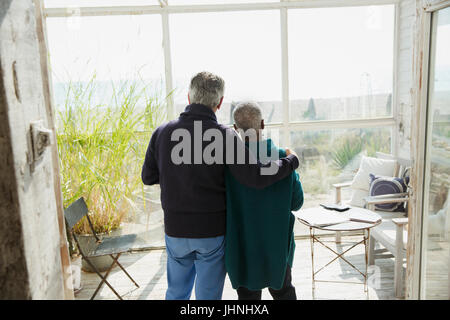 Affectionate senior couple enjoying beach view on sun porch Stock Photo