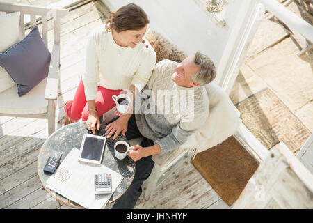 View from above mature couple drinking coffee and using digital tablet on sun porch Stock Photo